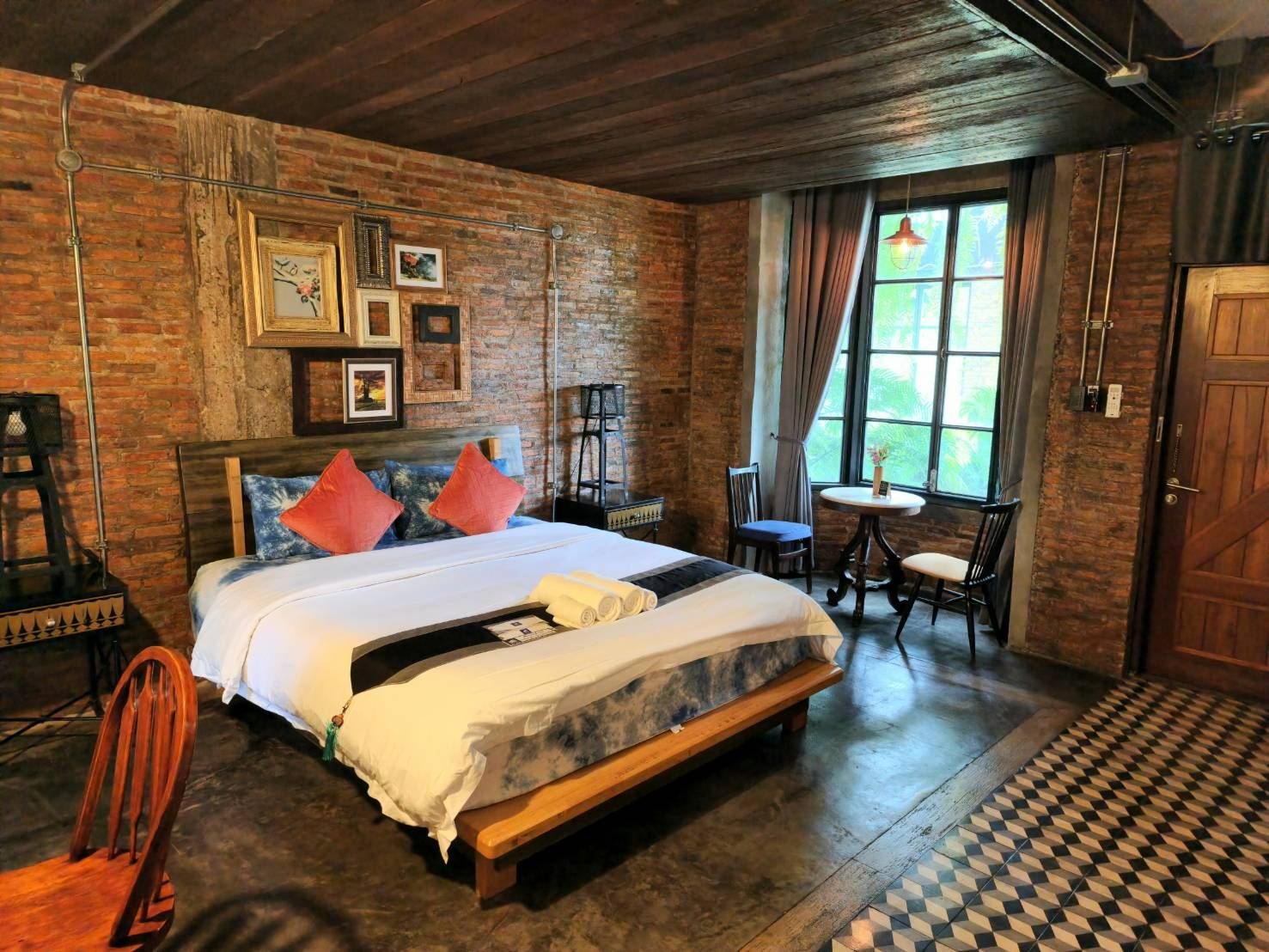 Deluxe room with brick walls, timber ceiling and checkered floor